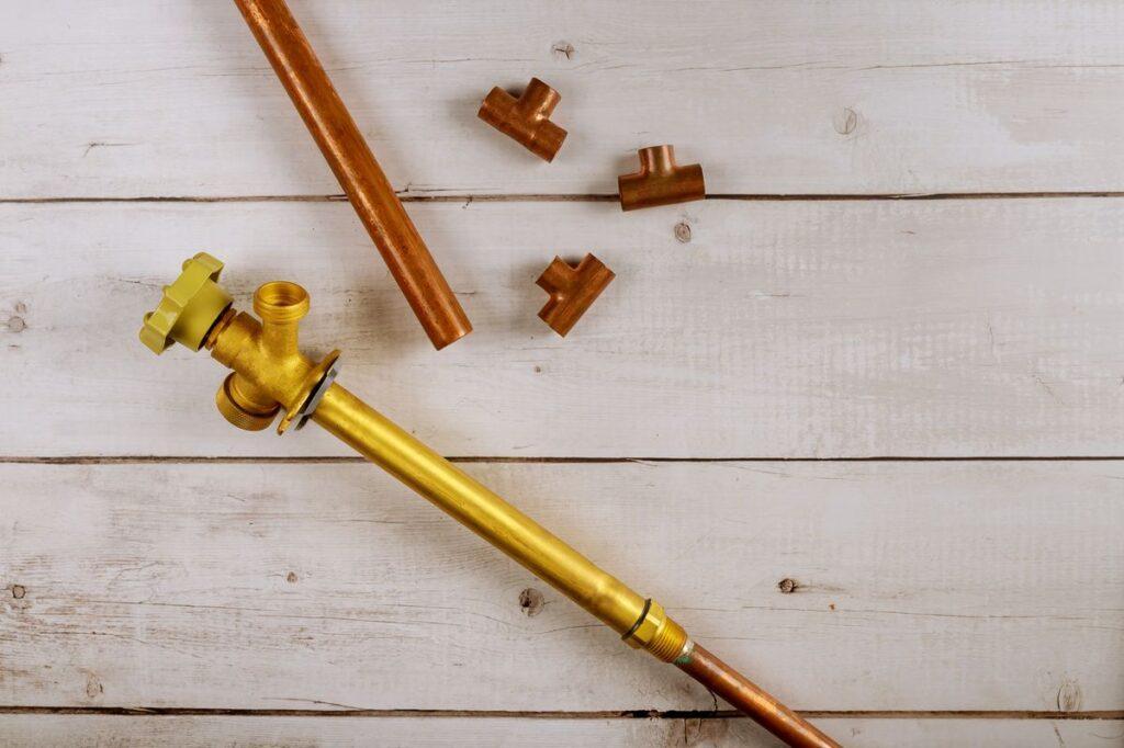 tuyaux en cuivre et raccords de plomberie posés sur un plan de travail