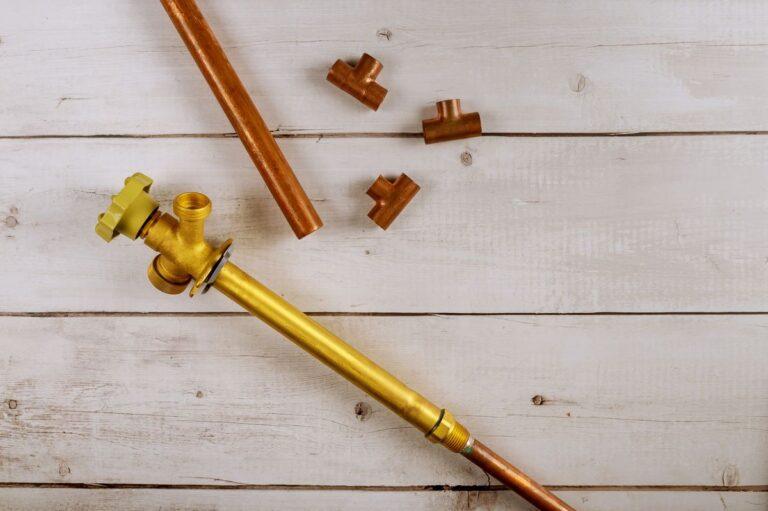 tuyaux en cuivre et raccords de plomberie posés sur un plan de travail